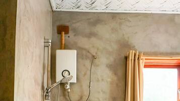 Une salle de bain avec une douche, une fenêtre avec des rideaux et un chauffe-eau visible.