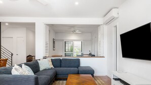 Un salon moderne avec un canapé d’angle, une table basse en bois et un téléviseur à écran plat.