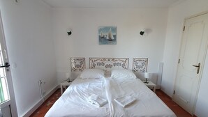 A bedroom with a large bed, white walls, a painting of sailboats, and a tiled floor. - HOLIDAY FLAT IN PATAIAS WITH TERRACE, POOL & DIRECT BEACH ACCESS (Mina)