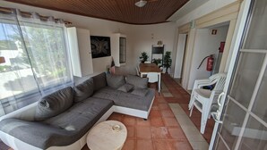 A living room with a grey sectional sofa, a round coffee table, and a dining area with a table and chairs. - HOLIDAY FLAT IN PATAIAS WITH TERRACE, POOL & DIRECT BEACH ACCESS (Mina)