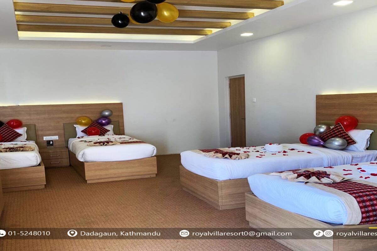 A hotel room with two beds, a wooden headboard, and a desk with a telephone and a water bottle.