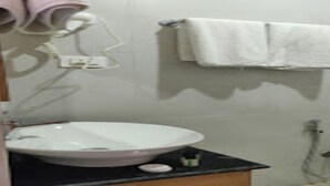 A bathroom with a white sink, a towel rack with two towels, a shower head, and a soap dispenser. - MeroStay 029 Royal Villa Resort (Tohka)