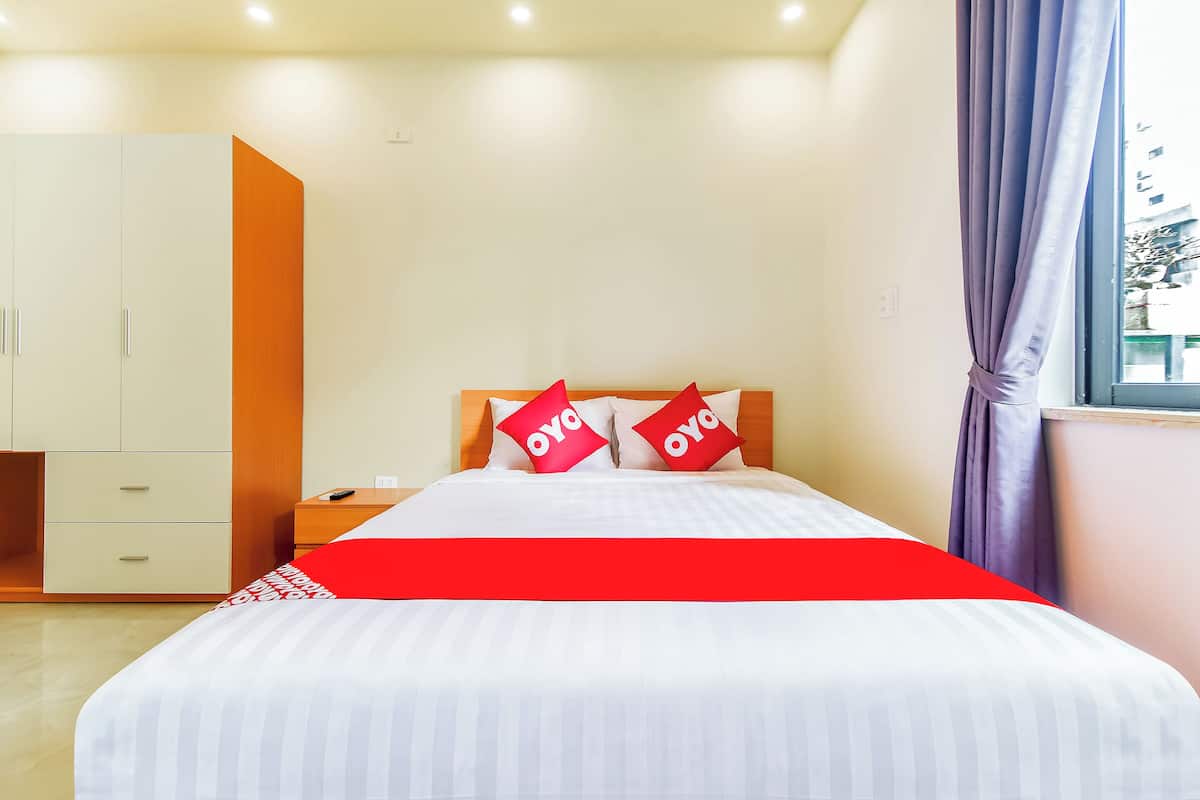 A hotel room with a bed, a wardrobe, a nightstand, and a window with curtains.