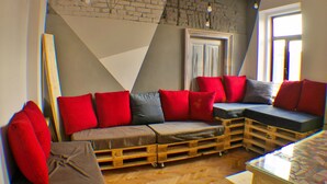 A modern living room with a sectional sofa, red and grey cushions, and a wooden floor.