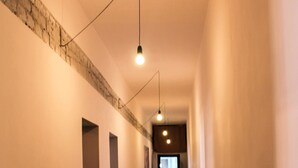 A hallway with a patterned floor, a wooden bench, a hanging light fixture, and a brick accent wall.