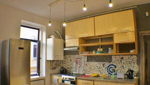 A kitchen with wooden cabinets, a refrigerator, a stove, and a tiled backsplash.