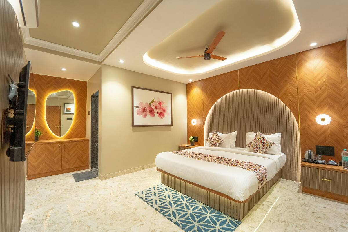 Quarto de hotel moderno com uma cama grande, ventoinha no teto, espelho e padrão de parede de madeira em espinha de peixe.
