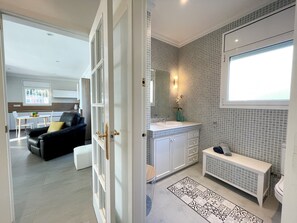 Une salle de bain moderne avec un mur recouvert de carreaux, un lavabo, un miroir et une fenêtre.