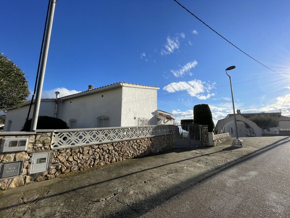 Un bâtiment avec un mur en pierre et un portail en métal, un ciel dégagé et un lampadaire.