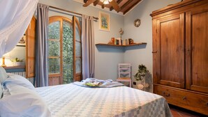 Une chambre à coucher avec un lit, une fenêtre avec des rideaux, une armoire en bois et une étagère remplie de livres.