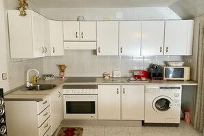 Een koelkast, een magnetron, een koffiezetapparaat/waterkoker, eettafels