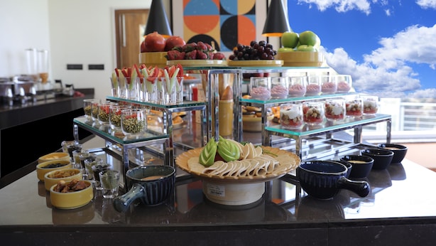 Un buffet proposant une variété de plats et de boissons, notamment des fruits, des pâtisseries et des condiments.