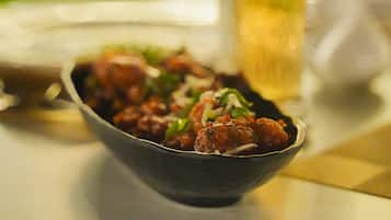A bowl of food and a glass of beverage on a table.