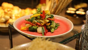 Un buffet proposant divers plats, notamment une assiette de légumes variés et un plat de pâtes.