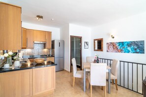 Eine moderne Küche mit Holzschränken, einer schwarzen Arbeitsplatte und einem Essbereich mit Tisch und Stühlen.