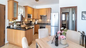 Eine moderne Küche mit Holzausbau, einer zentralen Kochinsel, Edelstahlgeräten und einem Essbereich mit Tisch und Stühlen.