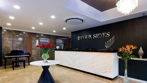 A hotel reception area with a marble floor, a grand piano, and a reception desk with a sign that reads "FOUR SIDES". - Four Sides Hotel (Istanbul)