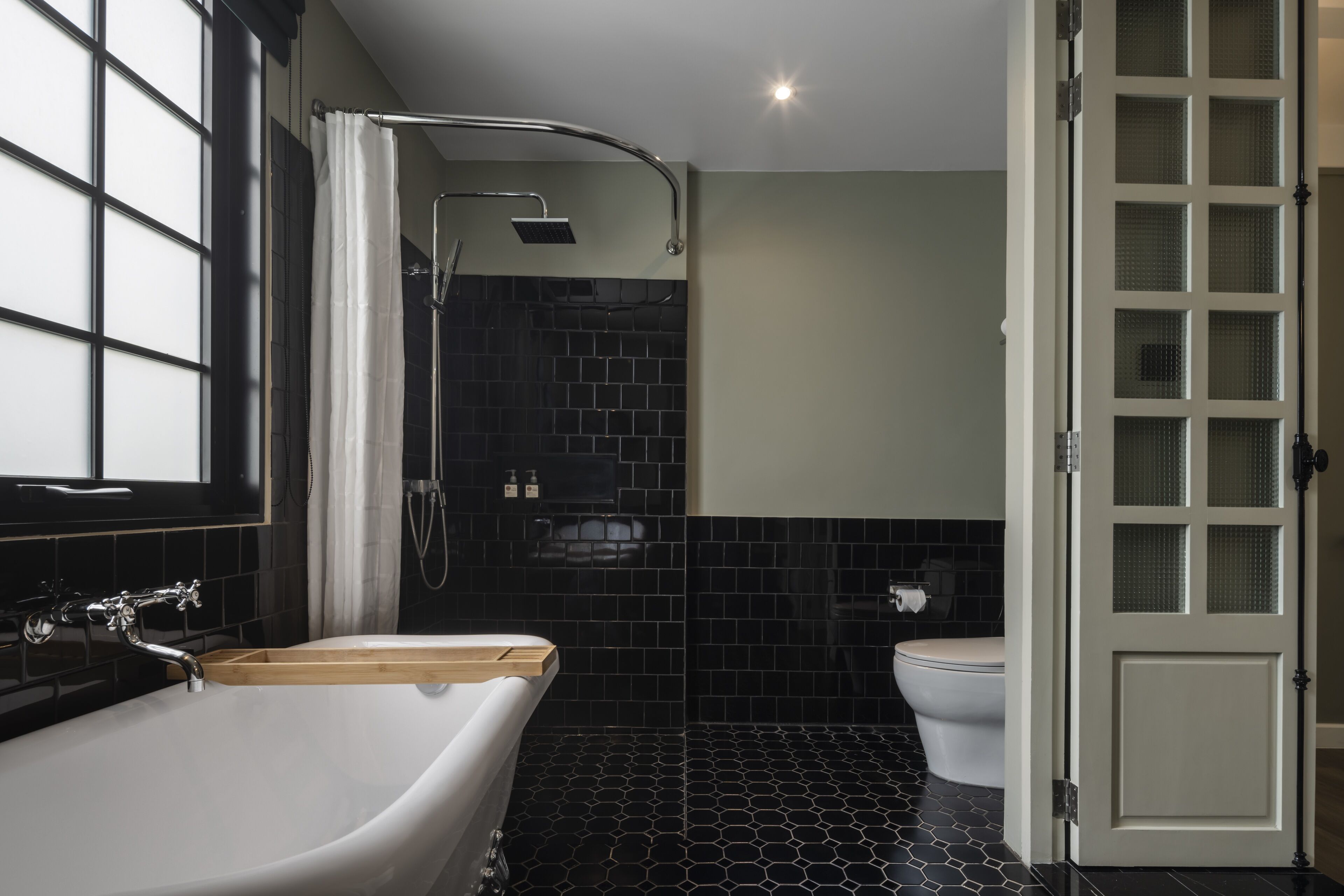 A modern bathroom with a freestanding bathtub, a shower with a handheld showerhead, and a toilet.