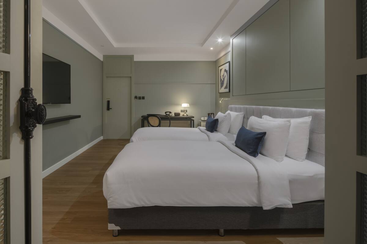 A modern hotel room with a large bed, a desk, and a flat-screen TV mounted on the wall.