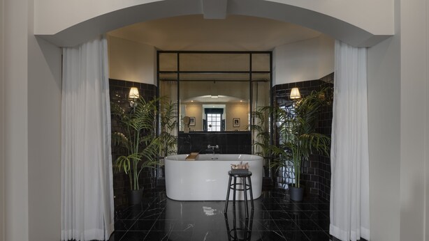 Un baño moderno con una bañera independiente, un espejo y dos plantas en macetas.