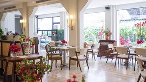 Un restaurante espacioso con techos altos, ventanas amplias y diferentes opciones de asientos, incluyendo mesas y sillas.