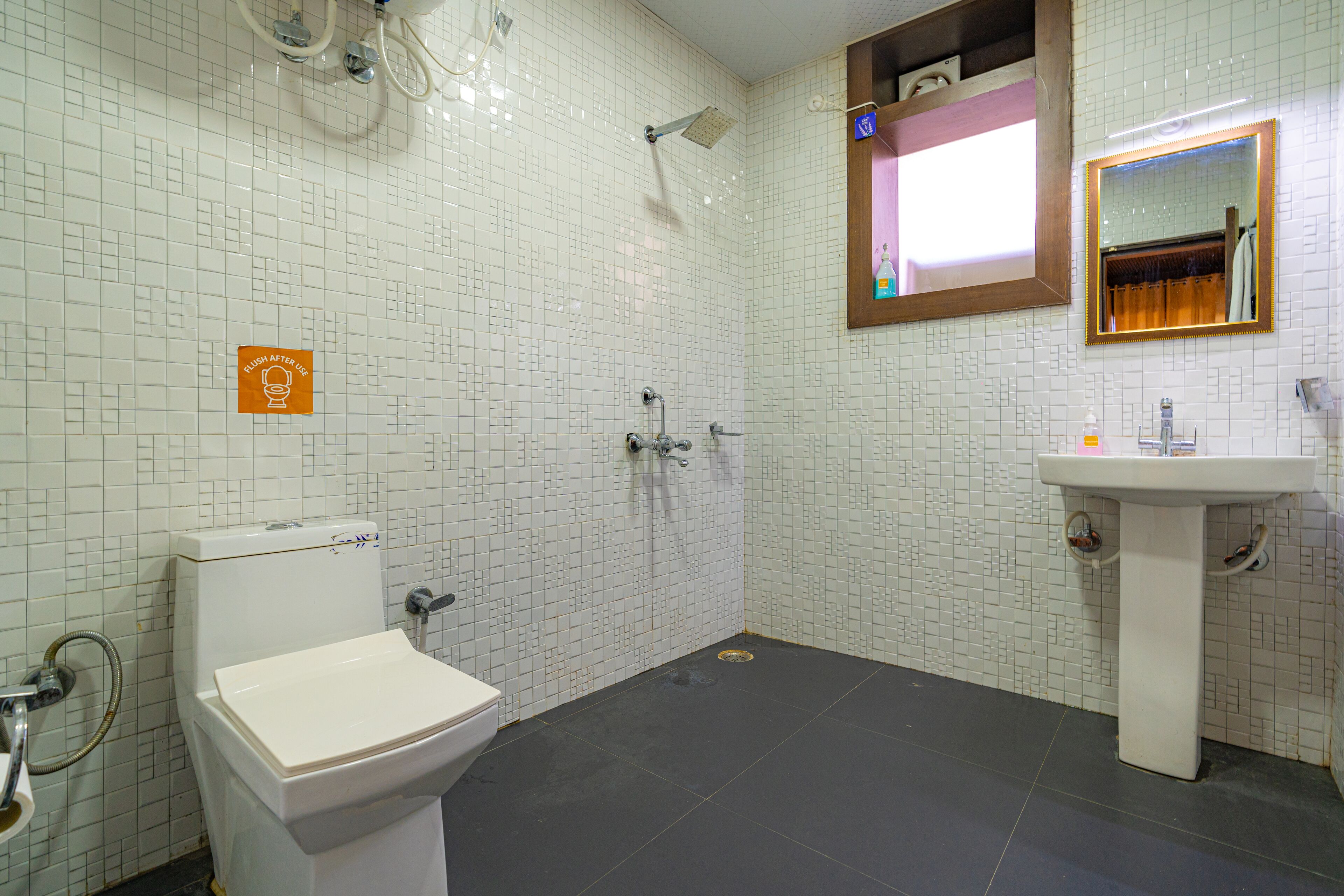 A bathroom with a toilet, shower, and sink.
