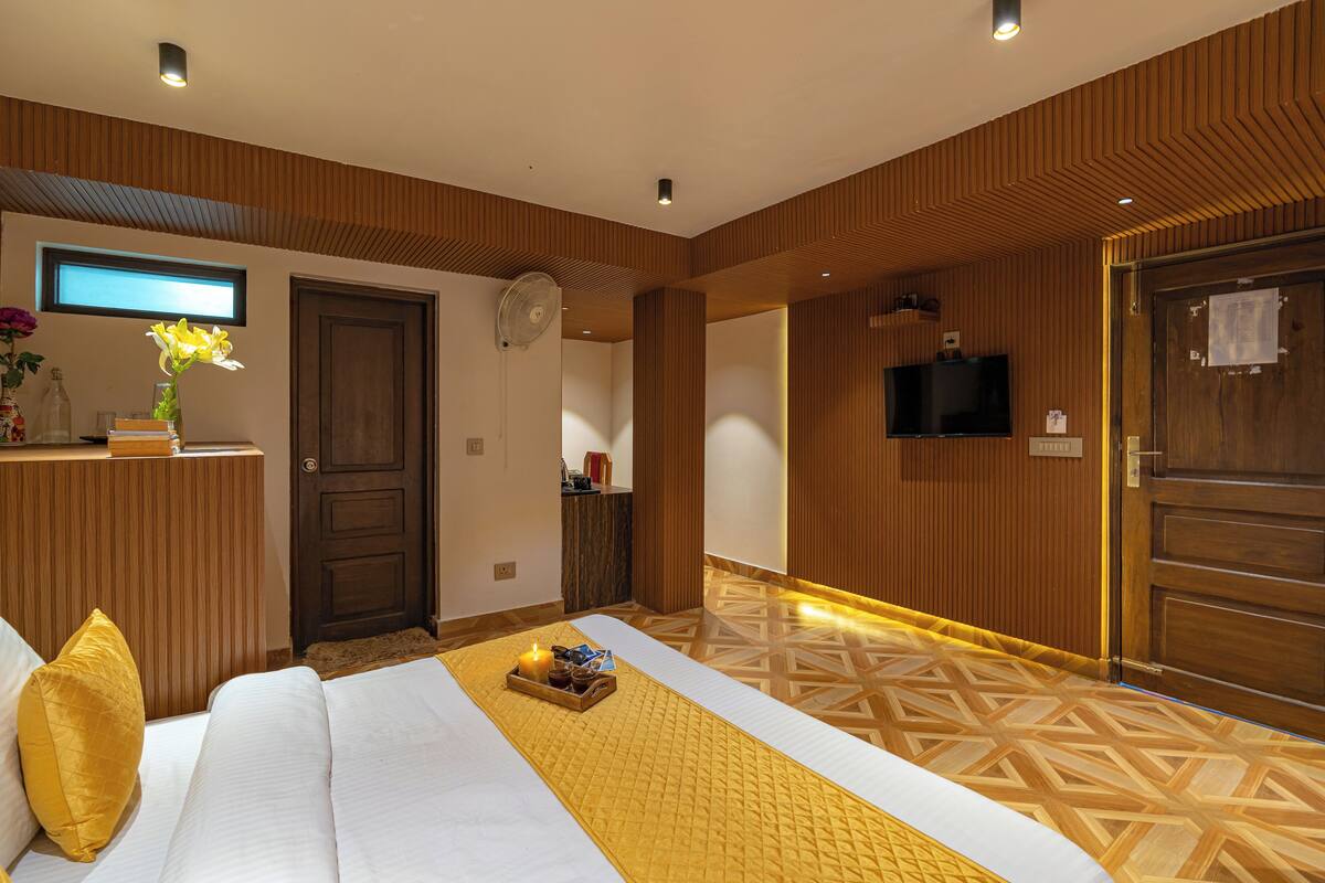 Ein Hotelzimmer mit Bett, Fernseher, einer Holzwand und einem Fenster.
