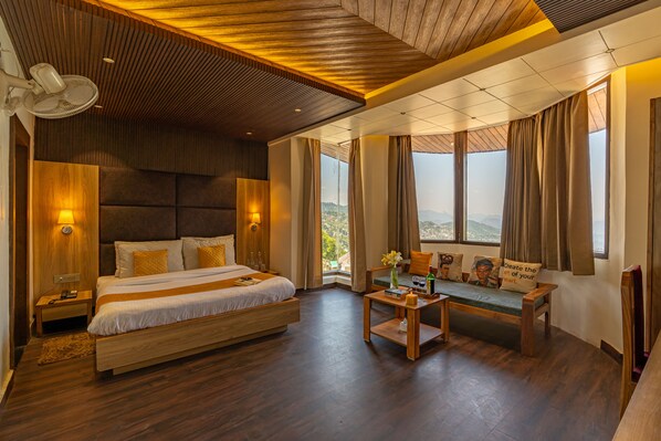 Une chambre d’hôtel moderne avec un grand lit, un coin salon offrant une belle vue et un plafond en bois.