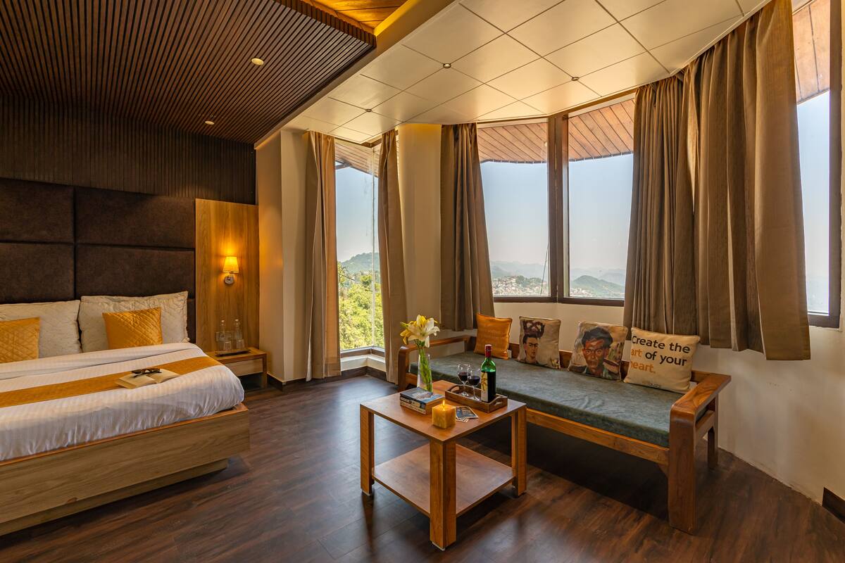 Ein modernes Hotelzimmer mit einem großen Bett, einer Couch, einem Holztisch und Blick auf die Berge.
