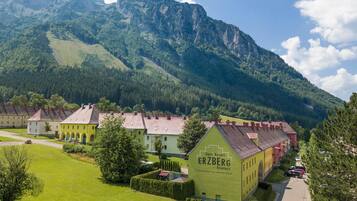 Un resort con el paisaje de una montaña como telón de fondo, que presenta un edificio destacado con el letrero "Alpin Resort ERZBERG".