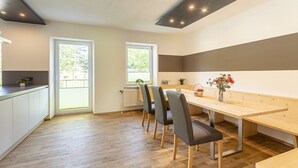 A modern kitchen with white cabinets, a wooden countertop, and a dining area with a wooden table and chairs. - Apartment in Alps with Stunning Views (No Deposit) (Eisenerz)