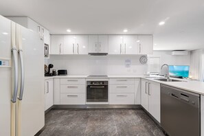 Eine moderne Küche mit weißen Schränken, einem Backofen, einem Geschirrspüler und einem großen Fenster mit Blick.