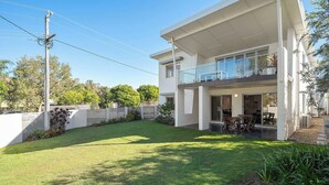 A modern two-story house with a covered patio and a well-maintained lawn. - Coochin Court | Walk to Dicky Beach (DICKY BEACH)