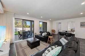 Una sala moderna con sofá, reposapiés y comedor con sillas.