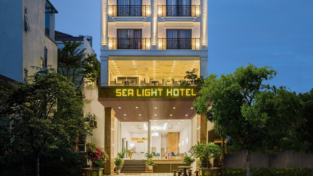 The exterior of the Sea Light Hotel with a modern facade, large glass windows, and a welcoming entrance with steps and potted plants. - SEA LIGHT HOTEL DA NANG (Da Nang)