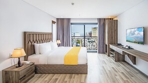 A hotel room with a bed, bedside table, lamp, desk, and a TV. - SEA LIGHT HOTEL DA NANG (Da Nang)