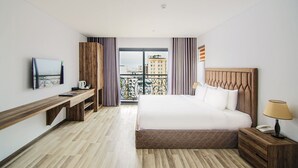 A hotel room with a bed, bedside table, lamp, and a TV on the wall. - SEA LIGHT HOTEL DA NANG (Da Nang)