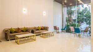 A modern lobby with a plush sofa, matching ottoman, and a seating area with colorful chairs. - SEA LIGHT HOTEL DA NANG (Da Nang)