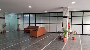 A spacious lobby with a brown sofa, potted plants, and a fire extinguisher mounted on the wall. - The Balcony Hotel (Hyderabad)