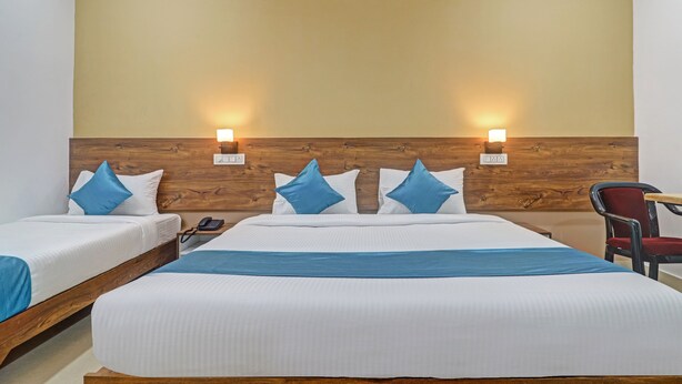 A hotel room with a large bed, two bedside tables, and a chair. - The Balcony Hotel (Hyderabad)