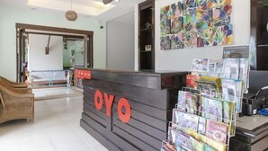 A reception area with a wooden reception desk, a wall of colorful abstract art, and a display of magazines. - OYO 1046 OYO 1046 Noppharat Resort (Krabi)