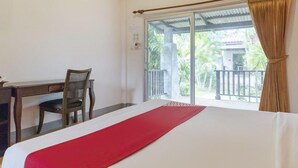 A hotel room with a bed, a desk, and a chair. There is a balcony with a view of greenery. - OYO 1046 OYO 1046 Noppharat Resort (Krabi)