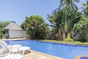 A swimming pool with tiled blue edges, surrounded by white lounge chairs and tropical vegetation. - OYO 1046 OYO 1046 Noppharat Resort (Krabi)
