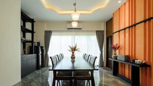 A modern dining area with a long table, chairs, and a vase of flowers. - OYO 1046 OYO 1046 Noppharat Resort (Krabi)