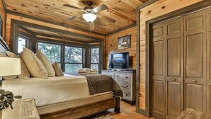 A bedroom with a bed, a ceiling fan, a TV, and a large wooden door. - Cherry Log Sky Bear | Cherry Log, GA (Blue Ridge)