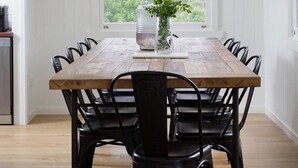 A dining table with a wooden top and black chairs, centered in a room with white walls and a large window. - Beautiful Farmhouse in Laceys Creek (Laceys Creek)