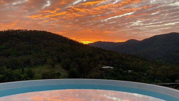 A hot tub on a wooden deck with a sunset view over a forested hill. - Beautiful Farmhouse in Laceys Creek (Laceys Creek)