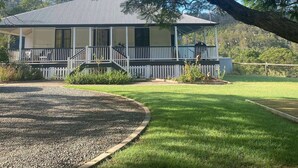 A two-story house with a covered porch, surrounded by a well-maintained lawn and trees. - Beautiful Farmhouse in Laceys Creek (Laceys Creek)