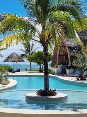 Una piscina al aire libre, sombrillas, sillones reclinables de piscina