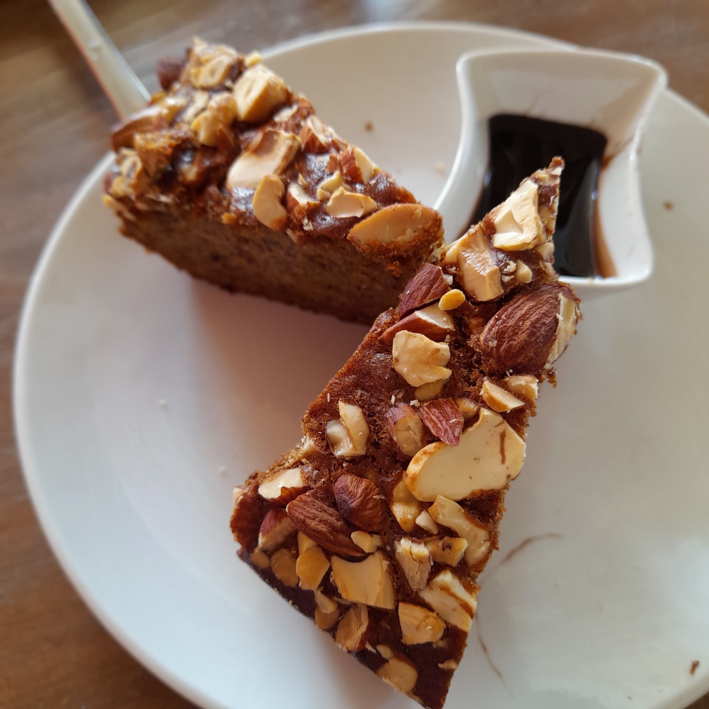 A slice of cake with almonds on a white plate.